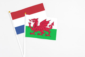 Wales and Netherlands stick flags on white background. High quality fabric, miniature national flag. Peaceful global concept.White floor for copy space.