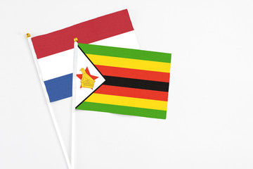Zimbabwe and Netherlands stick flags on white background. High quality fabric, miniature national flag. Peaceful global concept.White floor for copy space.