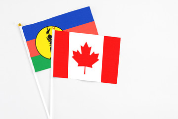 Canada and New Caledonia stick flags on white background. High quality fabric, miniature national flag. Peaceful global concept.White floor for copy space.