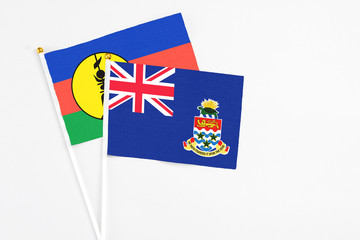 Cayman Islands and New Caledonia stick flags on white background. High quality fabric, miniature...