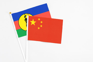 China and New Caledonia stick flags on white background. High quality fabric, miniature national flag. Peaceful global concept.White floor for copy space.