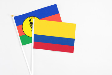 Colombia and New Caledonia stick flags on white background. High quality fabric, miniature national flag. Peaceful global concept.White floor for copy space.