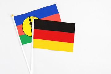 Germany and New Caledonia stick flags on white background. High quality fabric, miniature national flag. Peaceful global concept.White floor for copy space.