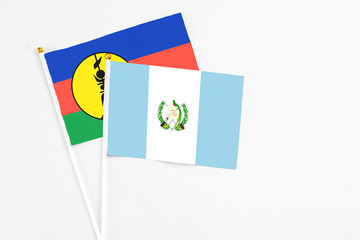 Guatemala and New Caledonia stick flags on white background. High quality fabric, miniature national flag. Peaceful global concept.White floor for copy space.