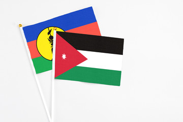 Jordan and New Caledonia stick flags on white background. High quality fabric, miniature national flag. Peaceful global concept.White floor for copy space.