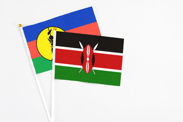 Kenya and New Caledonia stick flags on white background. High quality fabric, miniature national flag. Peaceful global concept.White floor for copy space.