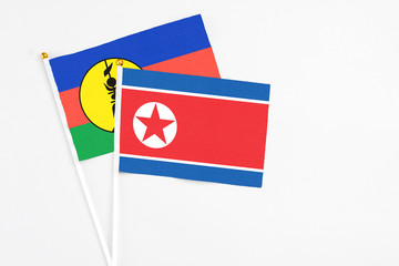North Korea and New Caledonia stick flags on white background. High quality fabric, miniature national flag. Peaceful global concept.White floor for copy space.