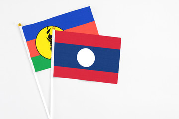 Laos and New Caledonia stick flags on white background. High quality fabric, miniature national flag. Peaceful global concept.White floor for copy space.