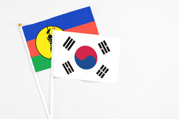 South Korea and New Caledonia stick flags on white background. High quality fabric, miniature national flag. Peaceful global concept.White floor for copy space.