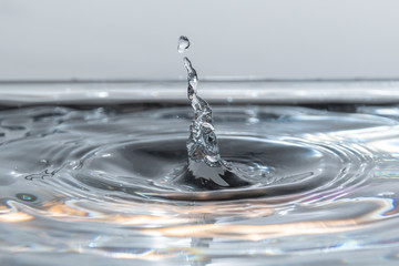 Wassertropfen fallen in das klare Wasser mit kleinen Wellen