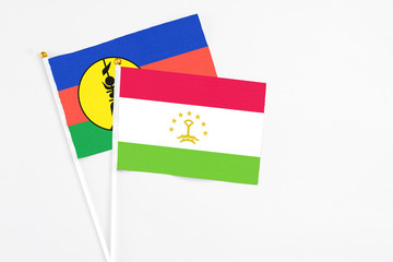 Tajikistan and New Caledonia stick flags on white background. High quality fabric, miniature national flag. Peaceful global concept.White floor for copy space.