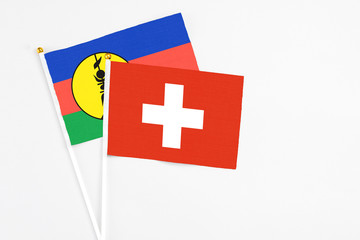 Switzerland and New Caledonia stick flags on white background. High quality fabric, miniature national flag. Peaceful global concept.White floor for copy space.