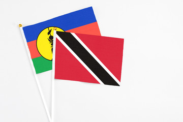 Trinidad And Tobago and New Caledonia stick flags on white background. High quality fabric, miniature national flag. Peaceful global concept.White floor for copy space.