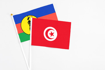 Tunisia and New Caledonia stick flags on white background. High quality fabric, miniature national flag. Peaceful global concept.White floor for copy space.