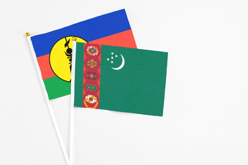 Turkmenistan and New Caledonia stick flags on white background. High quality fabric, miniature national flag. Peaceful global concept.White floor for copy space.