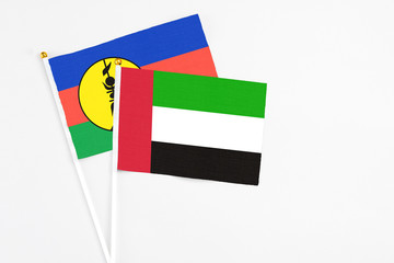 United Arab Emirates and New Caledonia stick flags on white background. High quality fabric, miniature national flag. Peaceful global concept.White floor for copy space.