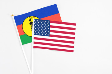 United States and New Caledonia stick flags on white background. High quality fabric, miniature national flag. Peaceful global concept.White floor for copy space.