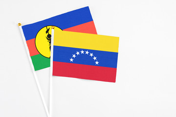 Venezuela and New Caledonia stick flags on white background. High quality fabric, miniature national flag. Peaceful global concept.White floor for copy space.
