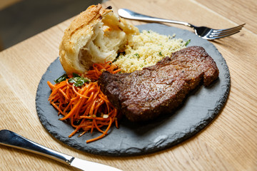 Piece of grilled pork meat with kuskus, spiced carrot and bread