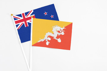 Obraz na płótnie Canvas Bhutan and New Zealand stick flags on white background. High quality fabric, miniature national flag. Peaceful global concept.White floor for copy space.
