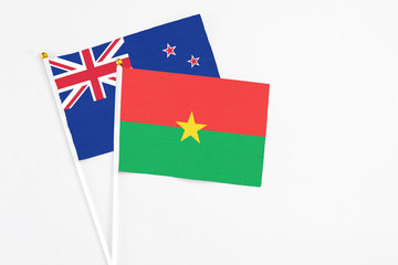 Burkina Faso and New Zealand stick flags on white background. High quality fabric, miniature national flag. Peaceful global concept.White floor for copy space.