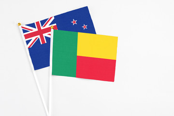 Benin and New Zealand stick flags on white background. High quality fabric, miniature national flag. Peaceful global concept.White floor for copy space.