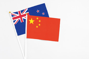 China and New Zealand stick flags on white background. High quality fabric, miniature national flag. Peaceful global concept.White floor for copy space.