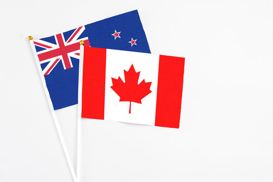Canada and New Zealand stick flags on white background. High quality fabric, miniature national flag. Peaceful global concept.White floor for copy space.