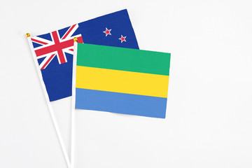 Gabon and New Zealand stick flags on white background. High quality fabric, miniature national flag. Peaceful global concept.White floor for copy space.