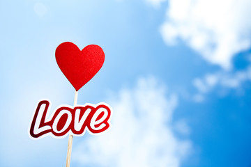 Obraz na płótnie Canvas paper cut word love and heart sign on sticks on blue sky background