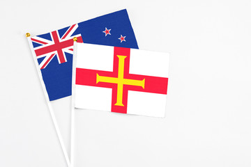 Guernsey and New Zealand stick flags on white background. High quality fabric, miniature national flag. Peaceful global concept.White floor for copy space.