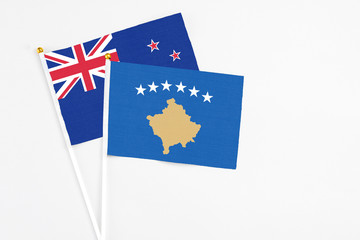 Kosovo and New Zealand stick flags on white background. High quality fabric, miniature national flag. Peaceful global concept.White floor for copy space.