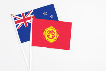 Kyrgyzstan and New Zealand stick flags on white background. High quality fabric, miniature national flag. Peaceful global concept.White floor for copy space.