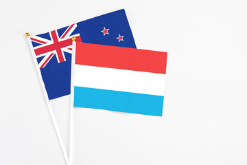 Luxembourg and New Zealand stick flags on white background. High quality fabric, miniature national flag. Peaceful global concept.White floor for copy space.