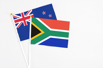 South Africa and New Zealand stick flags on white background. High quality fabric, miniature national flag. Peaceful global concept.White floor for copy space.