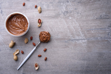 peanut butter and peanuts on grey background , top view