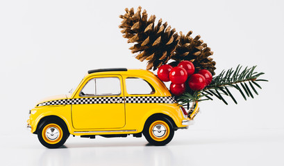 Christmas decorations are riding on an old car. Upcoming Christmas concept. Vintage style toy car. Cones and beads as Christmas tree decorations.