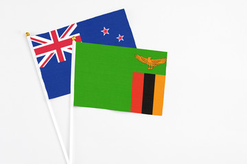 Zambia and New Zealand stick flags on white background. High quality fabric, miniature national flag. Peaceful global concept.White floor for copy space.