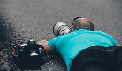 Professional photographer lies on the asphalt and takes a picture - Photos of cycling, sports - shooting with a telephoto lens
