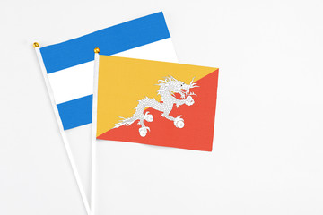 Bhutan and Nicaragua stick flags on white background. High quality fabric, miniature national flag. Peaceful global concept.White floor for copy space.