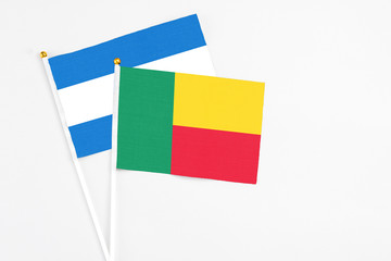 Benin and Nicaragua stick flags on white background. High quality fabric, miniature national flag. Peaceful global concept.White floor for copy space.