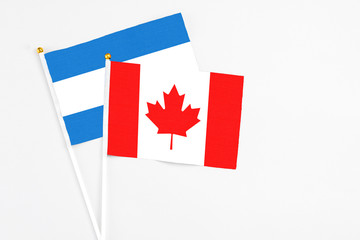 Canada and Nicaragua stick flags on white background. High quality fabric, miniature national flag. Peaceful global concept.White floor for copy space.