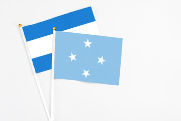 Micronesia and Nicaragua stick flags on white background. High quality fabric, miniature national flag. Peaceful global concept.White floor for copy space.