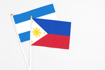 Philippines and Nicaragua stick flags on white background. High quality fabric, miniature national flag. Peaceful global concept.White floor for copy space.