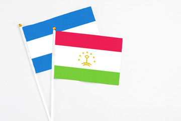 Tajikistan and Nicaragua stick flags on white background. High quality fabric, miniature national flag. Peaceful global concept.White floor for copy space.