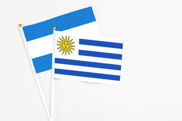 Uruguay and Nicaragua stick flags on white background. High quality fabric, miniature national flag. Peaceful global concept.White floor for copy space.