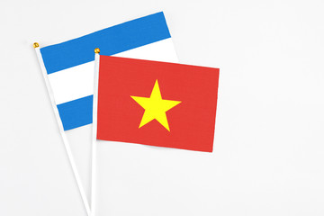 Vietnam and Nicaragua stick flags on white background. High quality fabric, miniature national flag. Peaceful global concept.White floor for copy space.