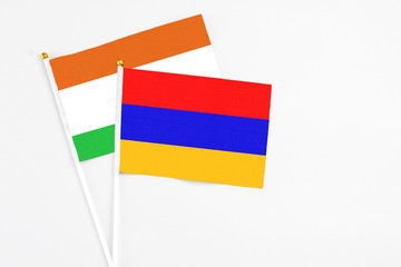Armenia and Niger stick flags on white background. High quality fabric, miniature national flag. Peaceful global concept.White floor for copy space.