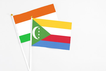 Comoros and Niger stick flags on white background. High quality fabric, miniature national flag. Peaceful global concept.White floor for copy space.