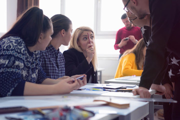 Beautiful young female teacher helping a student during class. Female Professor Holding Lecture to...